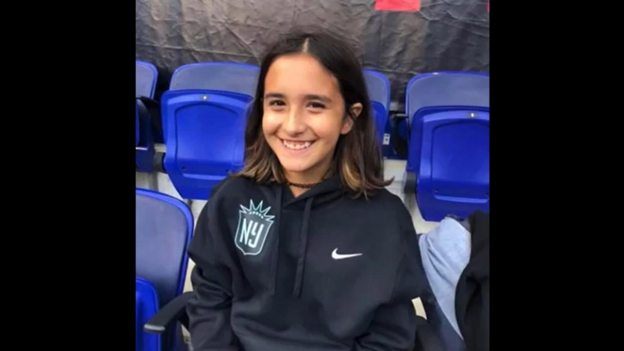 Young girl from New Jersey sitting in bleacher type setting.