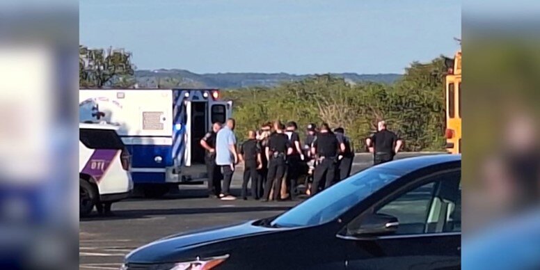 Photo of police officers surrounding an injured student resource officer next to an ambulance.