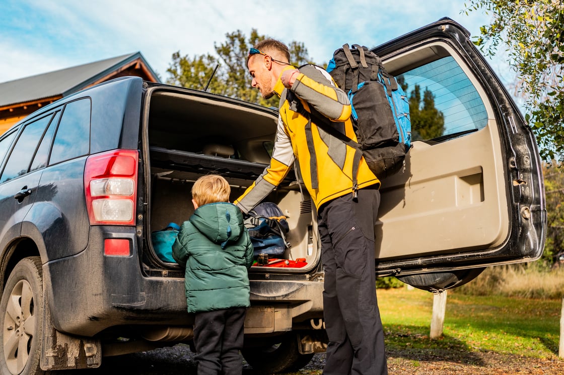 Dad and son outside the back of a minivan