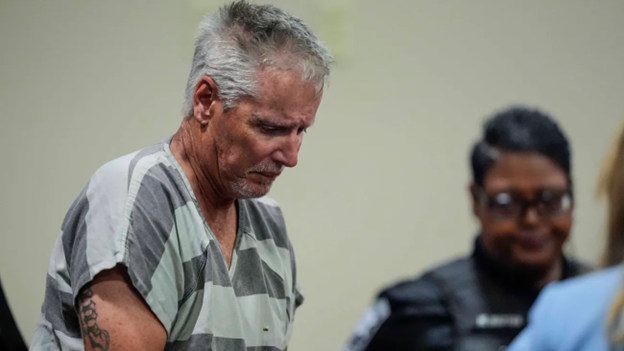 Photo shows Colin Gray in court standing next to a police officer.